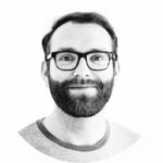 Profile picture from Tina. Black Glases, short, dark hair, Black short beard with a smile.