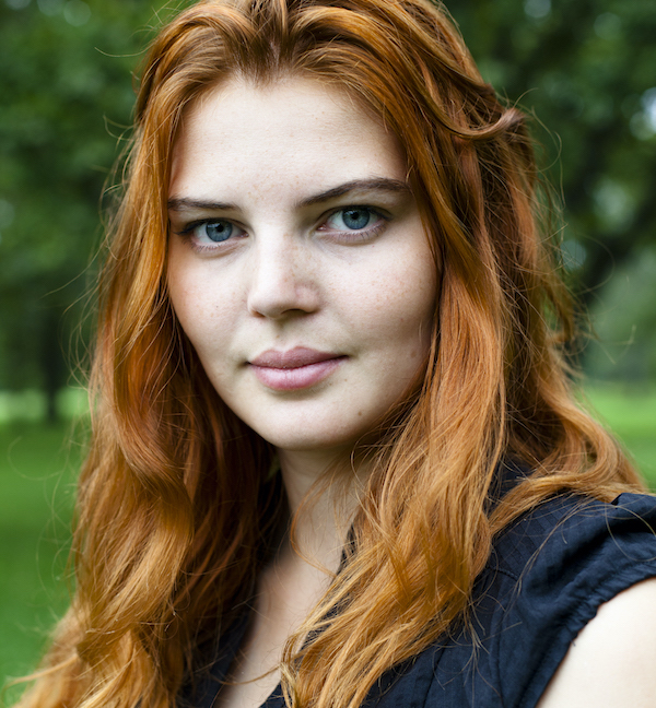 Profile picture from Maja. Long, red hair, black dress, with a smile