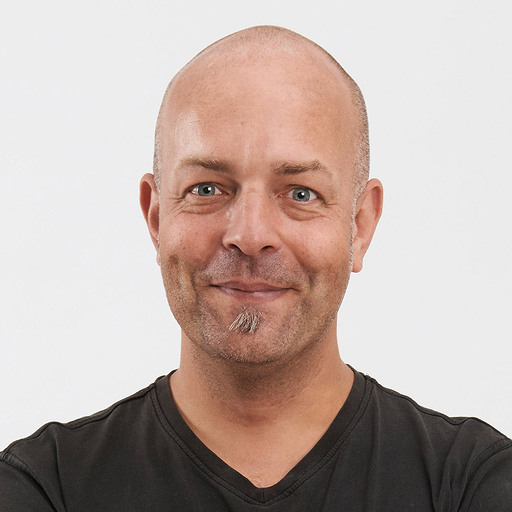 Profil picture from Joschi, with a smile, no hair and a black shirt.